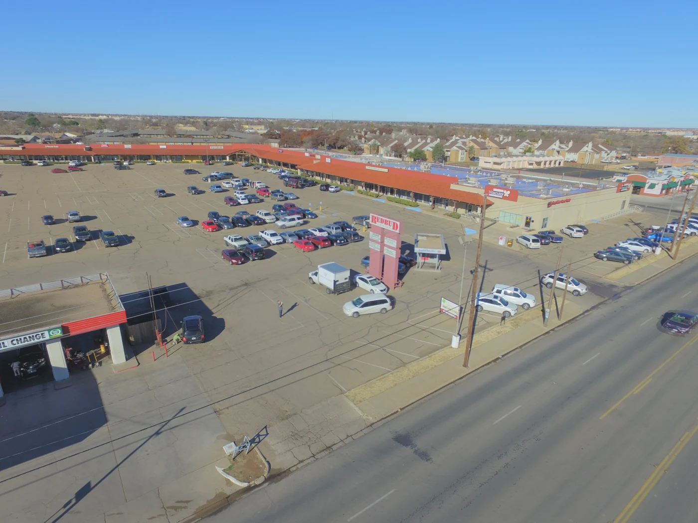 Redbud Center's red tile roof storefronts and parking area, photographed in 2015